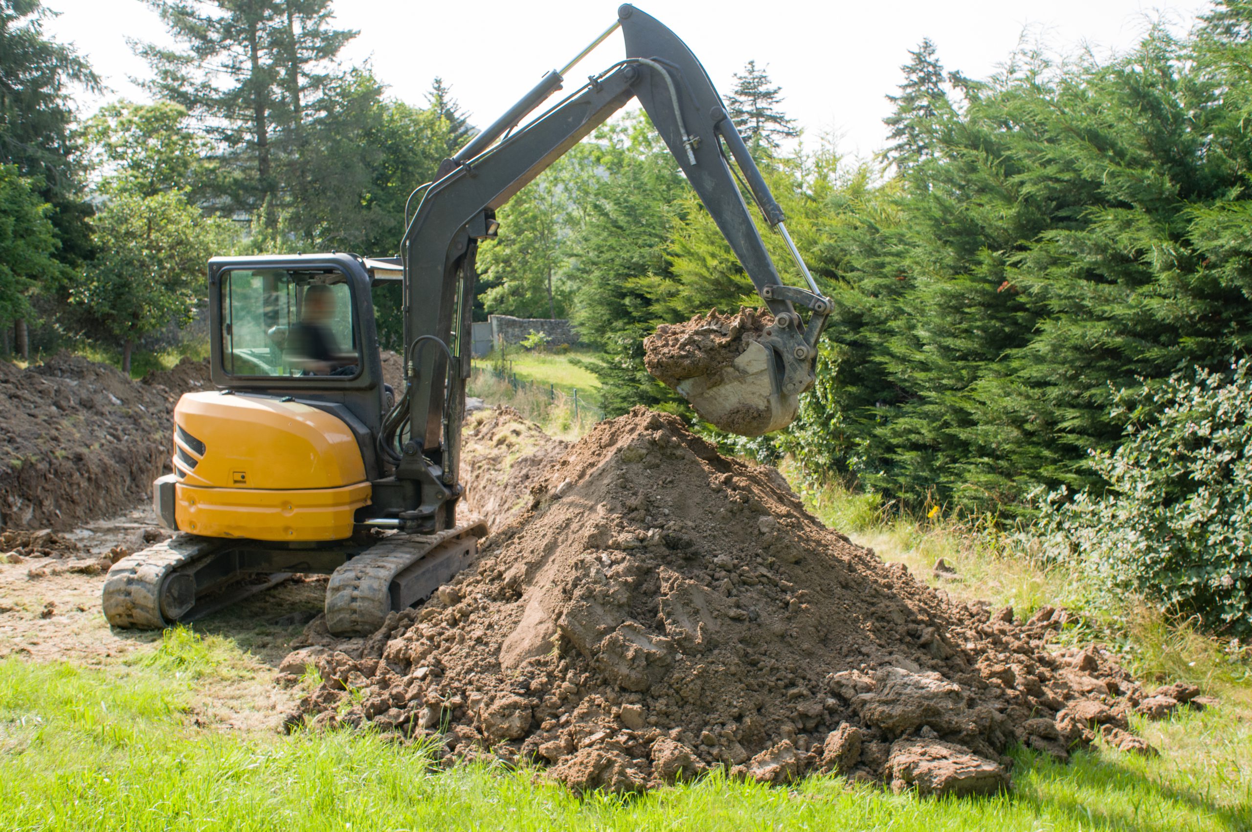A mini digger and a pile of soil